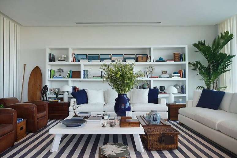 52. Sala ampla decorada com sofá branco, tapete listrado e poltronas de couro – Foto: Radar Design