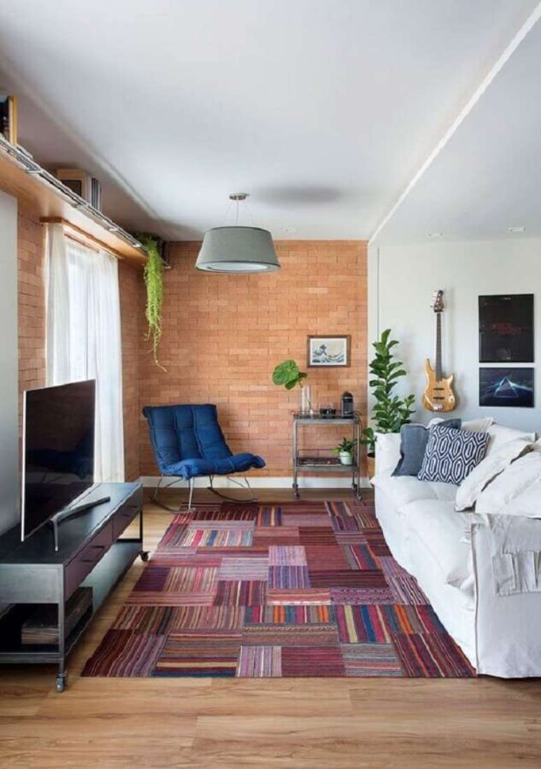 56. Sofá branco para sala de estar decorada com parede de tijolinho e tapete estampado – Foto: Casa de Valentina