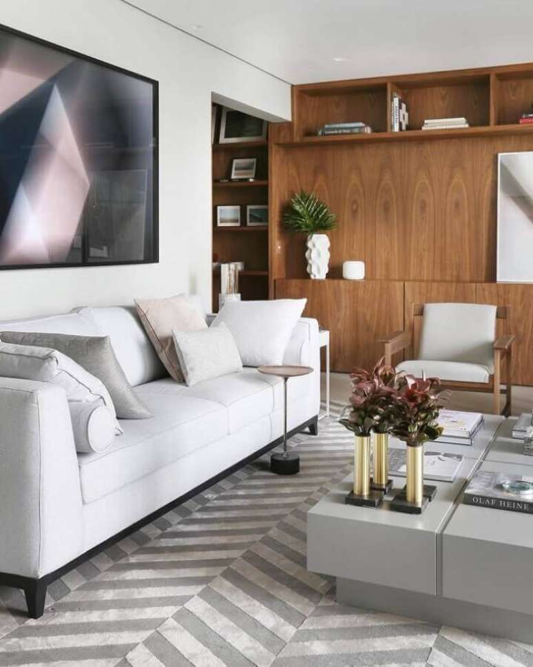 57. Sofá branco para sala de estar decorada com tapete cinza e estante de madeira – Foto: Simone Saccab – Arquiteta