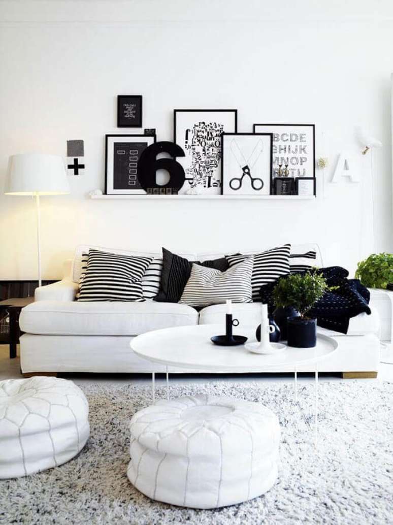 59. Sala minimalista decorada com sofá branco e vários quadros apoiados em prateleira estreita – Foto: Futurist Architecture