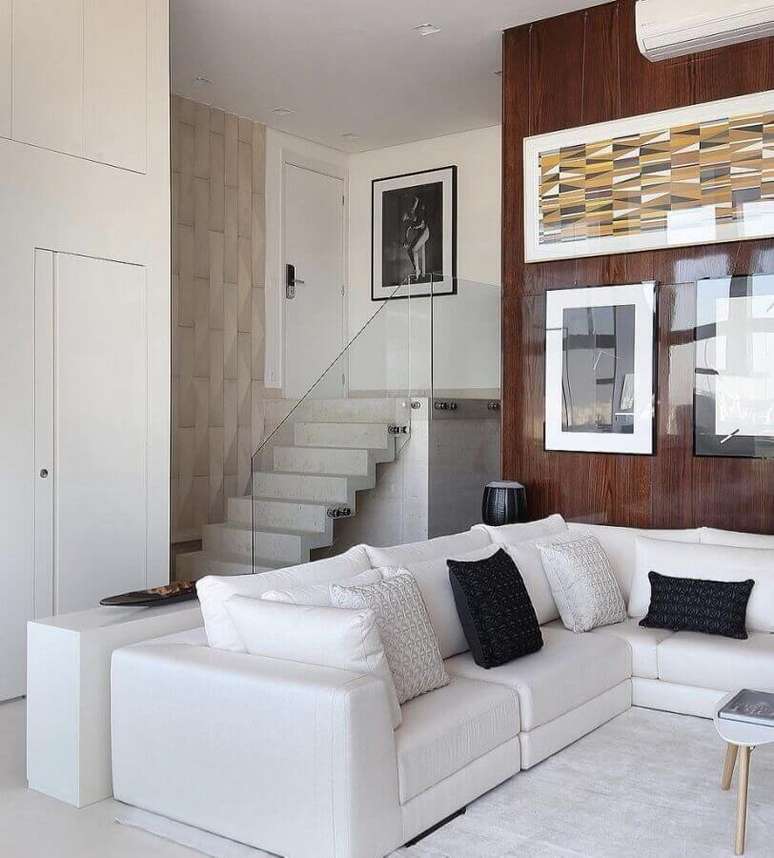 61. Sofá de canto branco para sala com parede revestida de madeira – Foto: Reedcore