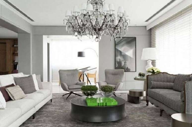 35. Tapete cinza para sala decorada com dois modelos diferentes de sofá e lustre candelabro – Foto: Roberto Migotto