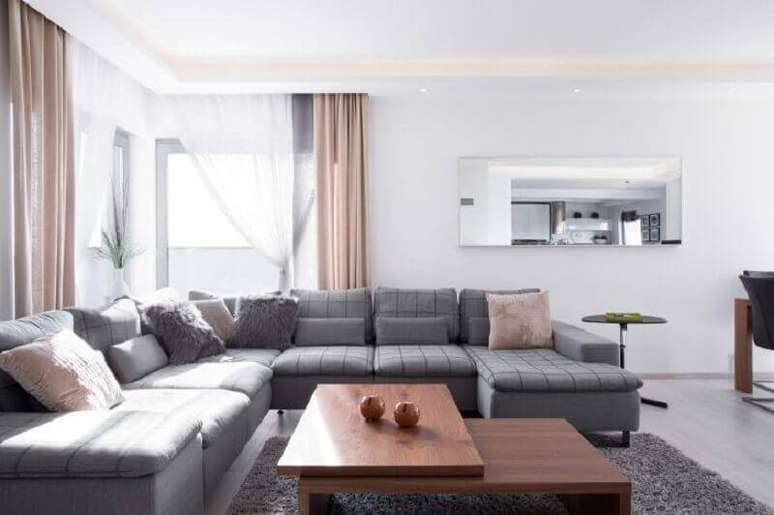 37. Tapete cinza para sala decorada com sofá de canto e cortinas e almofadas na cor rosa claro – Foto: Istock