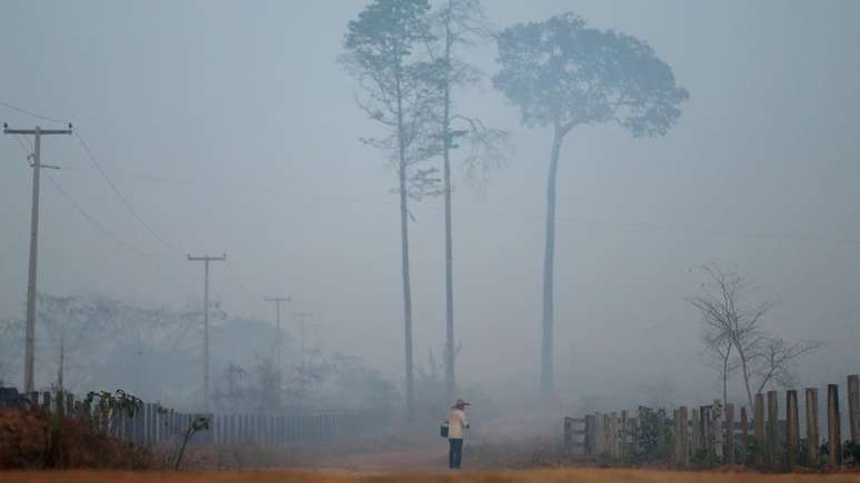 Homem caminha em estrada em Porto Velho em meio à fumaça; ex-presidente afirma que uma parte das queimadas acontecendo atualmente nas florestas é 'proposital'