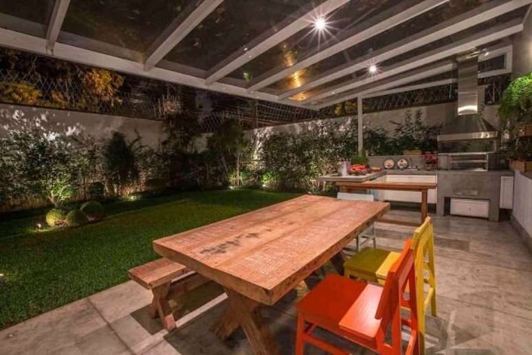 56. Varanda gourmet integrada ao jardim conta com mesa e cadeira de madeira colorida. Fonte: Revista Viva Decora
