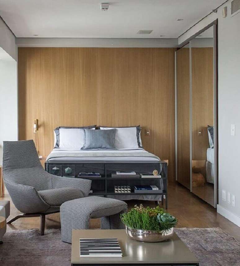 14. Poltrona com puff para quarto de casal cinza com guarda roupa espelhado e parede com revestimento de madeira – Foto: Triplex Arquitetura