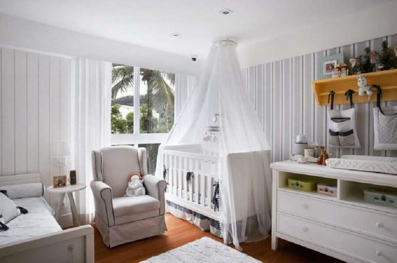29. Poltrona para quarto de bebê todo branco decorado com prateleira amarela e papel de parede listrado – Foto: Escala Arquitetura