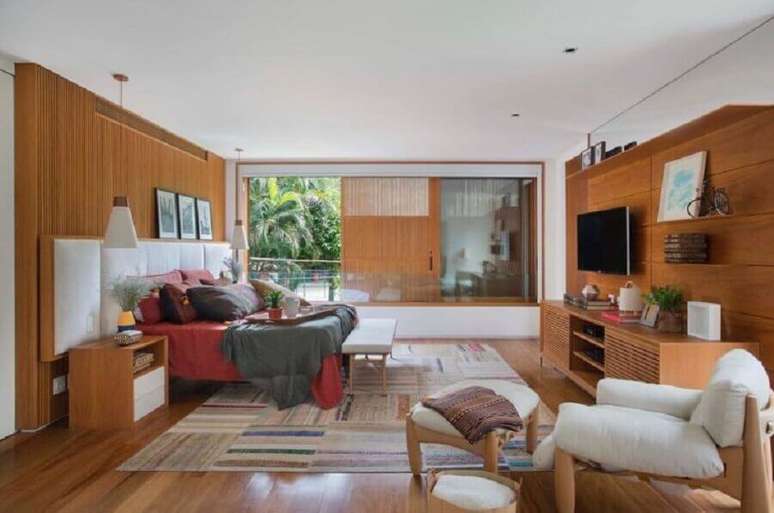 42. Poltrona para quarto de casal amplo com revestimento e m&oacute;veis de madeira &ndash; Foto: Escala Arquitetura