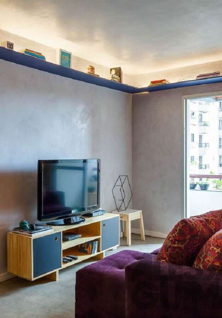 15. Decoração simples com rack para sala pequena com parede de cimento queimado e sofá roxo – Foto: Pinterest