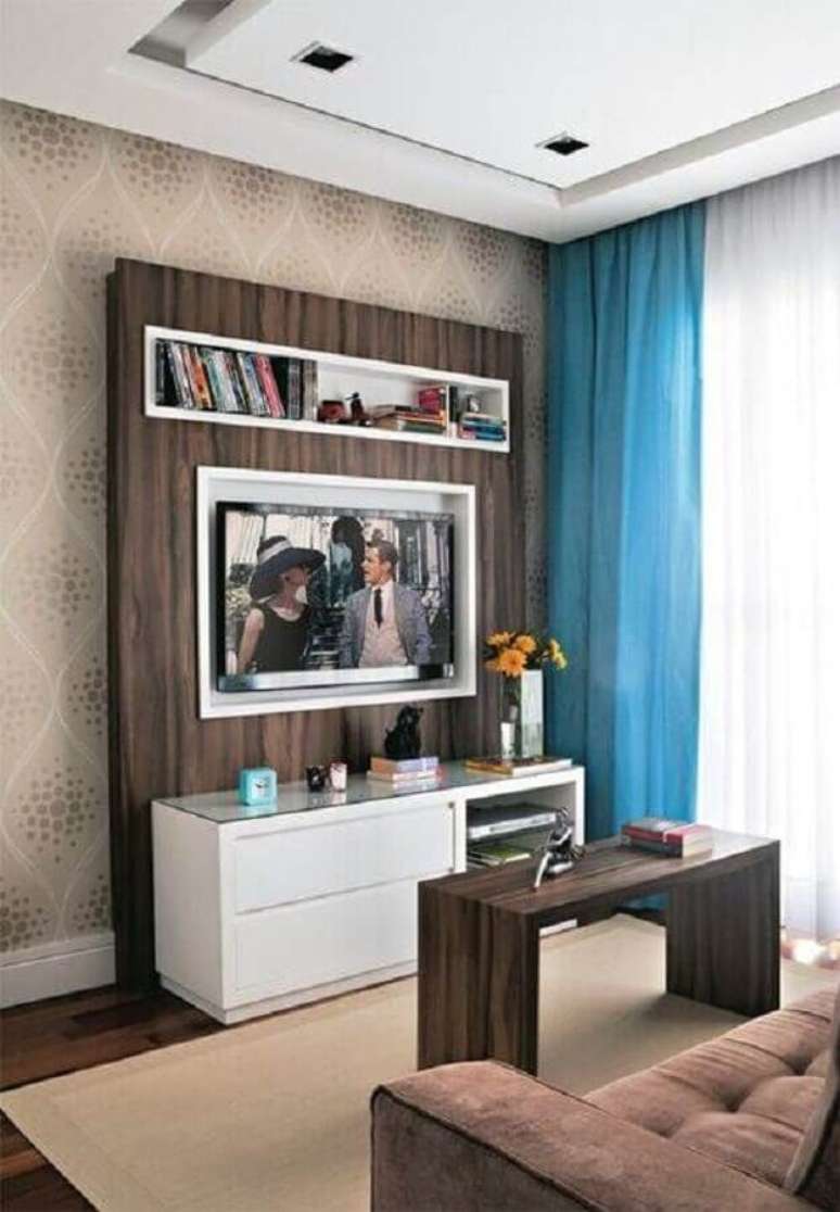 42. Decoração simples com rack com painel para sala pequena com cortina azul – Foto: Webcomunica