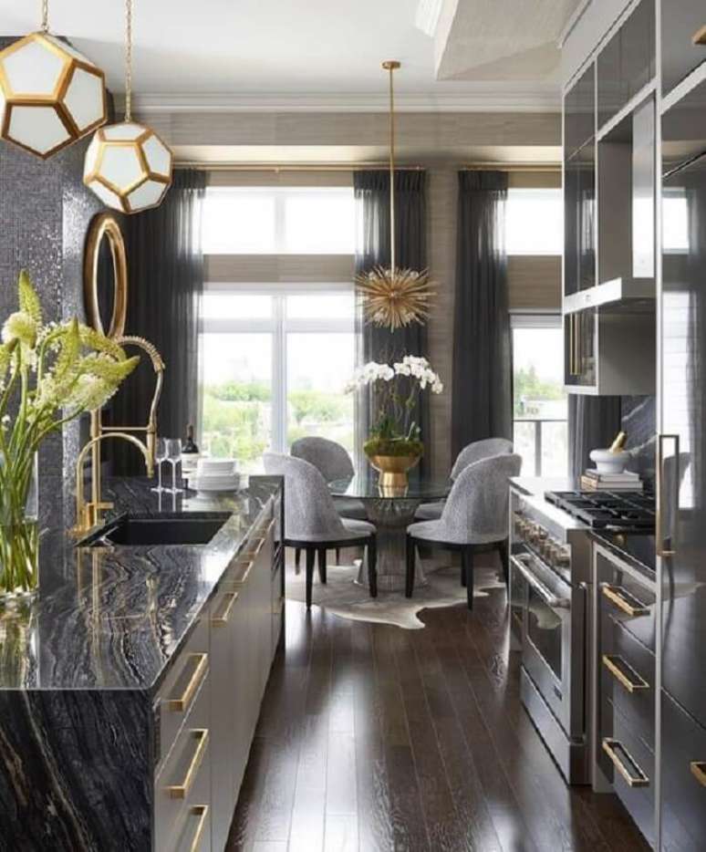 34. Cozinha com decora&ccedil;&atilde;o luxuosa e torneira gourmet dourada. Fonte Revista Viva Decora