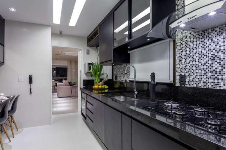 42. Cozinha planejada com pastilha preta e torneira gourmet de alum&iacute;nio. Projeto por Vanja Maia