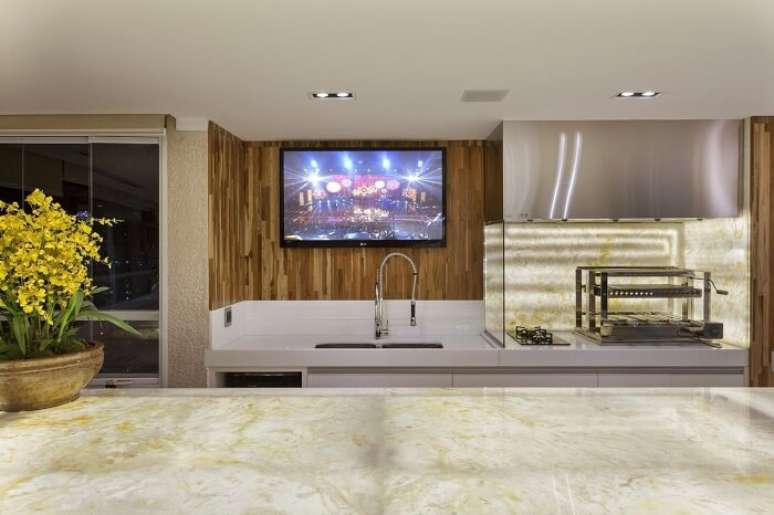 66. Varanda decorada com bancada de m&aacute;rmore e torneira do tipo gourmet. Projeto por Iara Kilaris