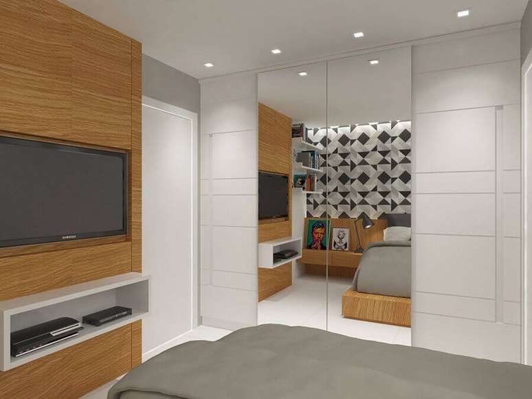 16. Decoração com painel de madeira e guarda roupa branco com espelho para quarto clean – Foto: Tripper Arquitetura