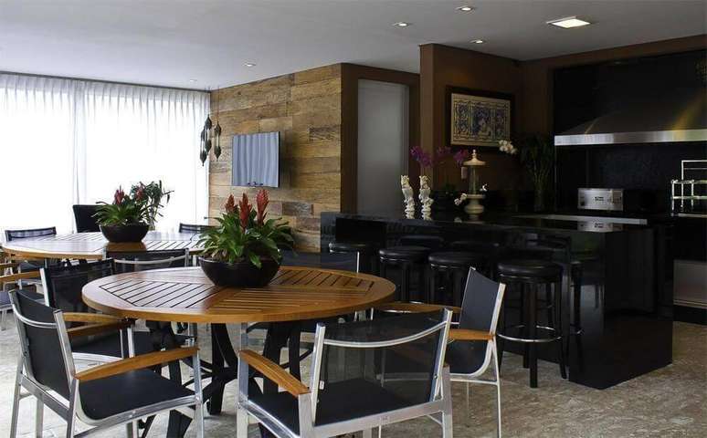 38. A &aacute;rea gourmet combina a mesa de madeira e a cor preta, mesclando moderno e cl&aacute;ssico. Projeto por Fabio Morozini.