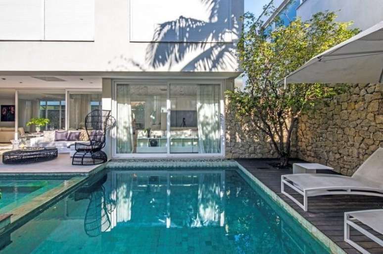 63. Muro revestido com pedras faz parte desse projeto de casas com piscina. Projeto por Cat&ecirc; Poli Paisagismo