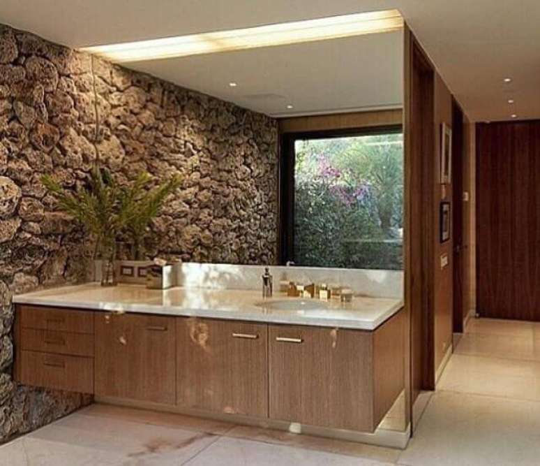 24. A parede do lavabo com pedras grandes ganha um efeito incrível junto ao espelho grande. Projeto por Karol Oetinger.