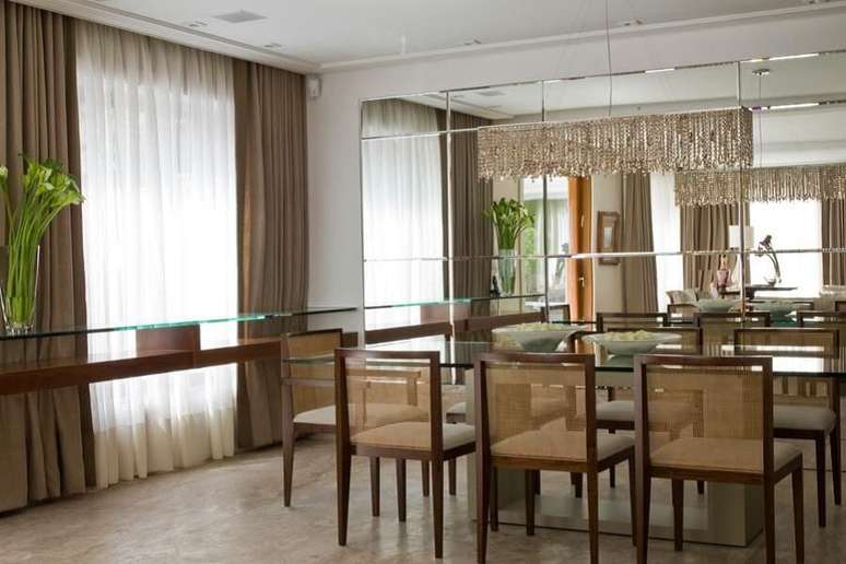 37. Sala de estar muito sofisticada com espelho grande, dando mais amplitude ao ambiente.