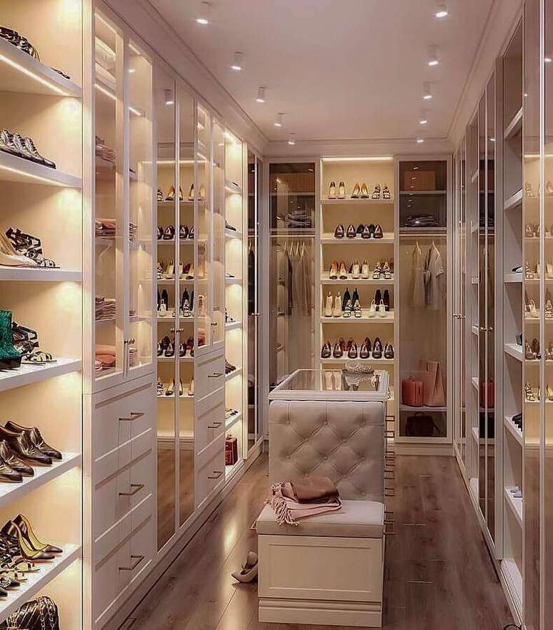 23. Closet luxuoso pequeno decorado com m&oacute;veis planejados e puff junto com ilha &ndash; Foto: Dicas de Mulher