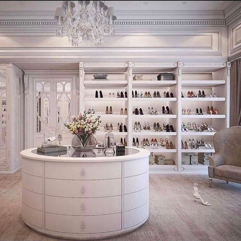 37. Closet luxuoso amplo decorado com ilha redonda e lustre de cristal &ndash; Foto: Pinosy