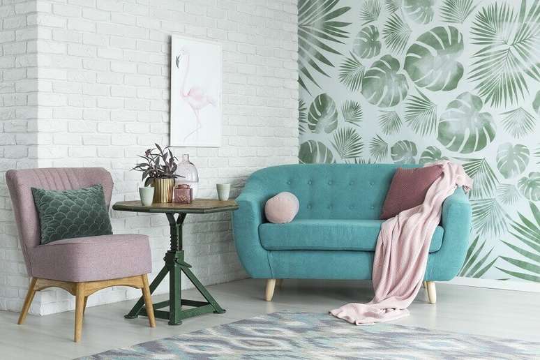 9. Sala de estar decorada com sofá azul e papel de parede com folhagens – Foto: Habitissimo