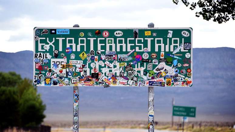 Placa de trânsito da 'Estrada para Extraterrestres', coberta com adesivos, na Rota 375