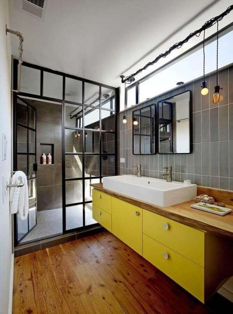15. Banheiro com decoração industrial, bancada de madeira e armários amarelos – Foto: Robert Nebolon Architects