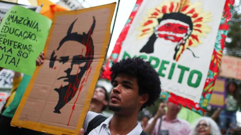 Manifestante no Rio de Janeiro exibe cartaz satirizando Bolsonaro; pauta ambiental deverá estar no discurso do presidente brasileiro na ONU