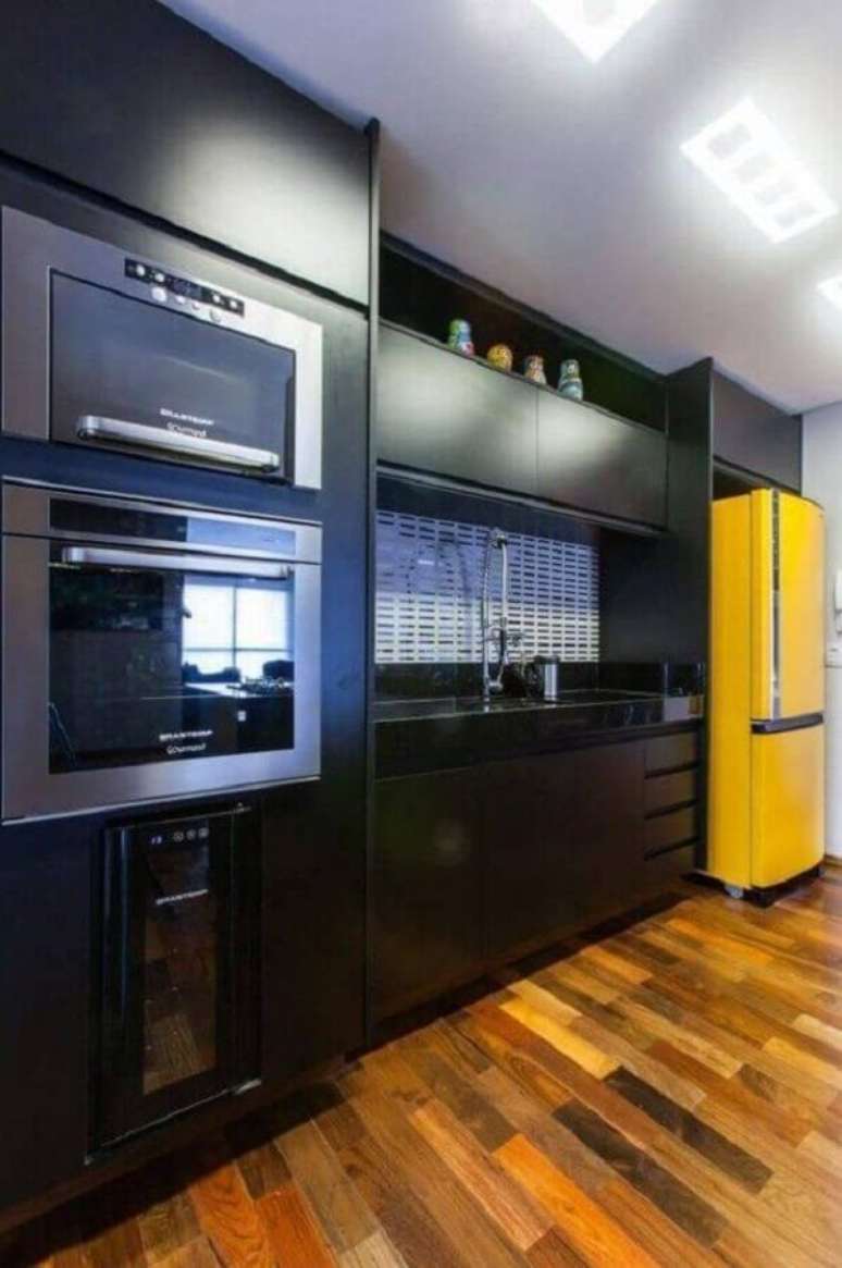 38. Decoração com piso de madeira para cozinha amarela e preta com armários planejados – Foto: Pinterest