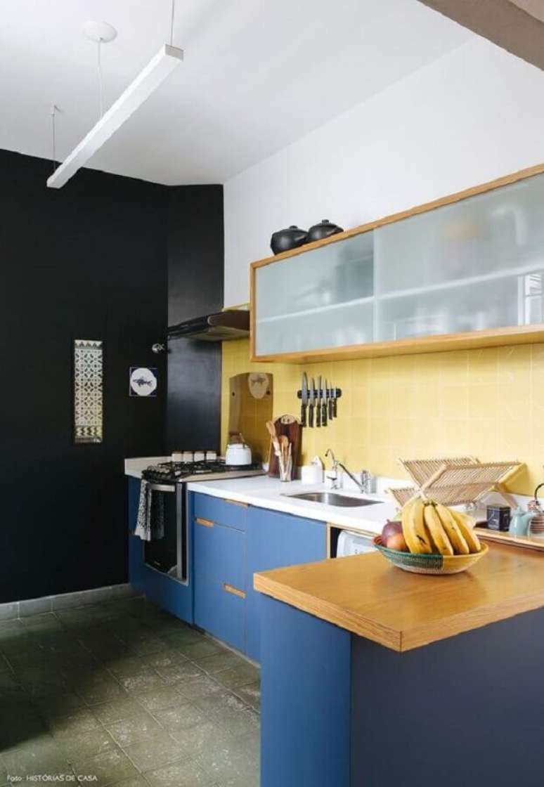 47. Decoração para cozinha amarela e azul com bancada de madeira e parede preta – Foto: Histórias de Casa