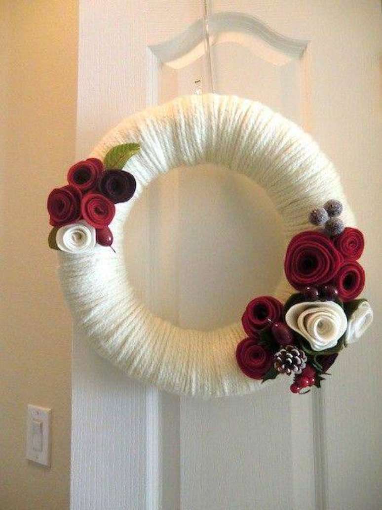 90. Guirlanda branca com detalhes de flores vermelhas combina com as festas de natal e ano novo.