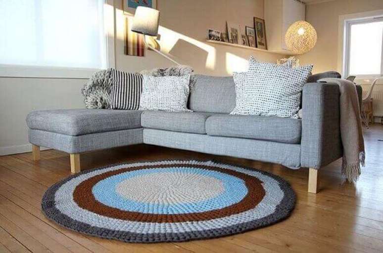 1- O tapete de crochê redondo em várias cores tem anel cinza combinando com a mesma cor do sofá. Fonte: 321Achei