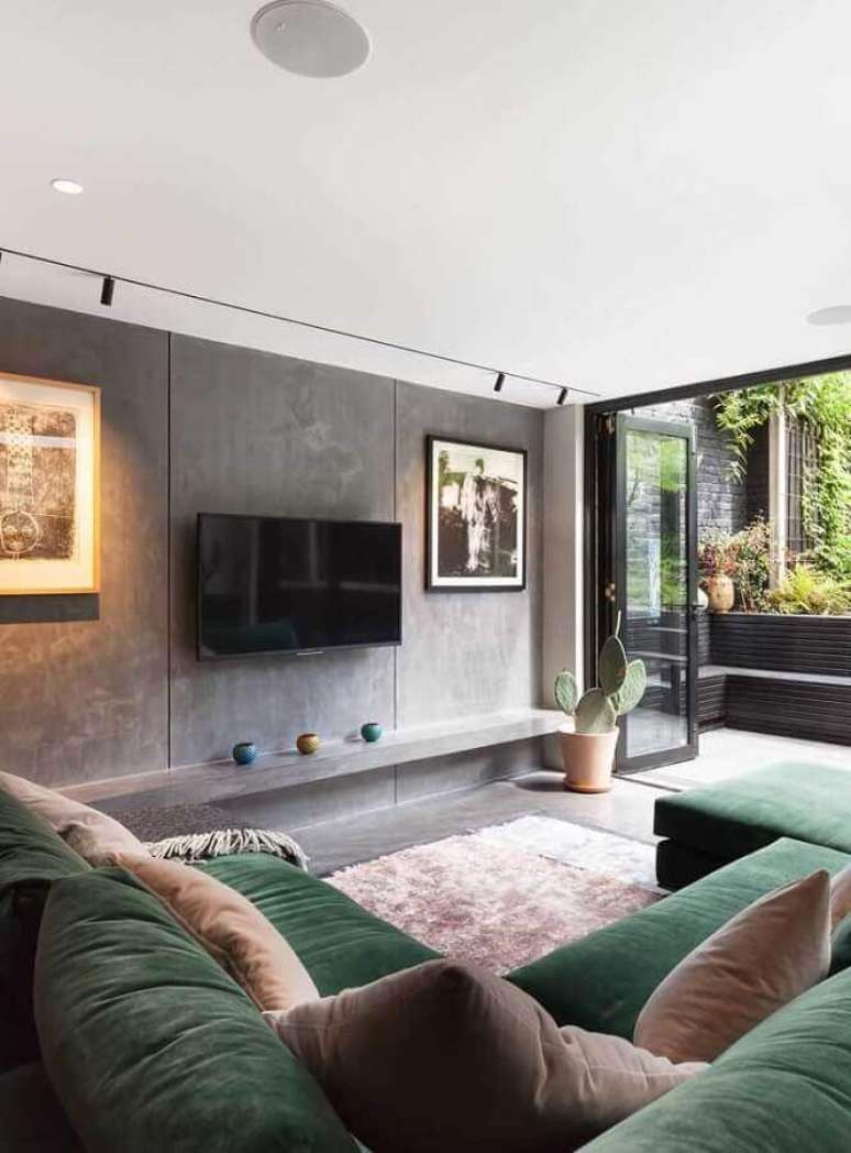 57. Sala moderna decorada com parede de cimento queimado e sofá verde musgo de canto – Foto: Pinterest