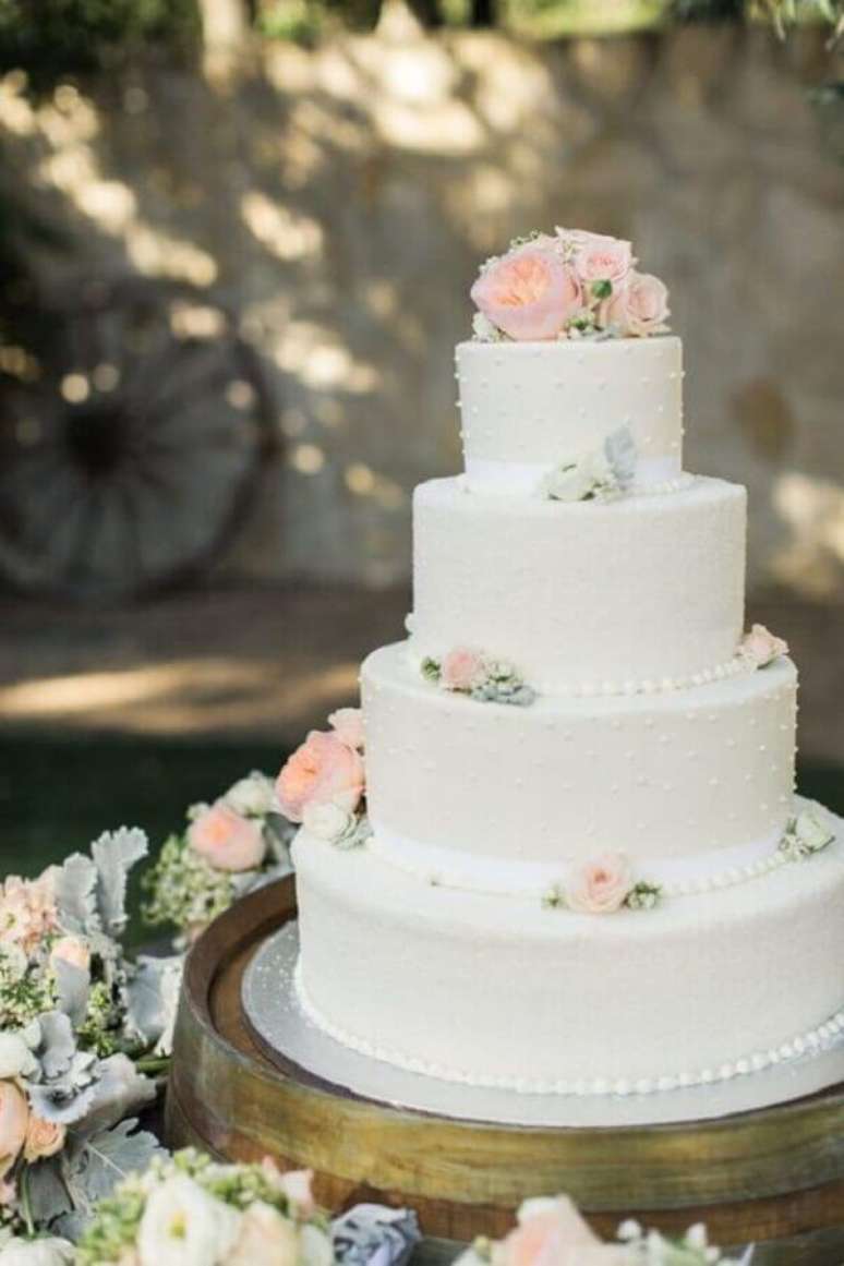 3. Modelo clássico de bolo de casamento branco com 4 andares e decorado com flores – Foto: iCasei