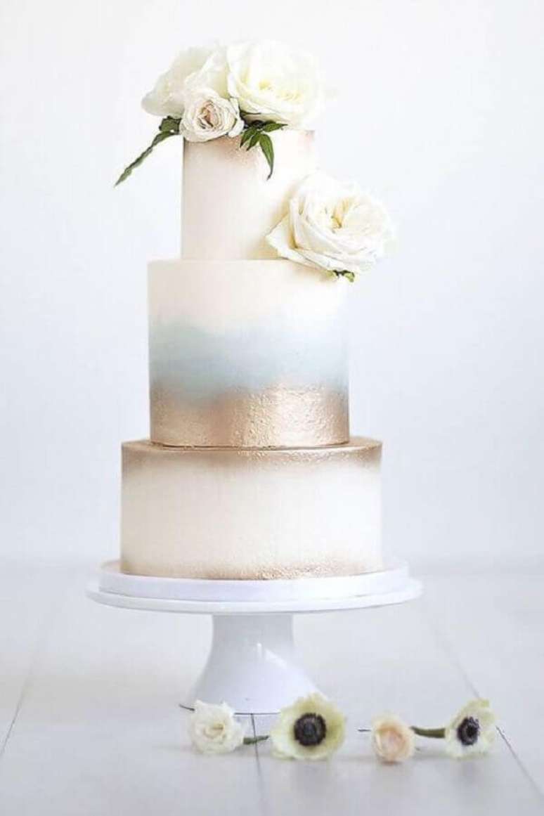 84. Lindo e moderno bolo de casamento com flores no topo e acabamento dourado – Foto: ELLE Decoration