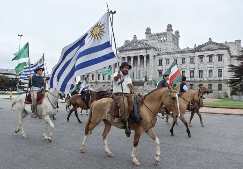 Homens a cavalo levam bandeira do Uruguai perto do Congresso do pa&iacute;s em Montevid&eacute;u
16/04/2002 REUTERS/Andres Stapff