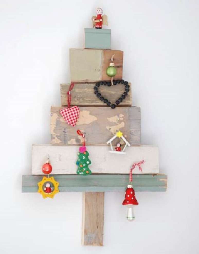 40. Tocos de madeira e enfeites formam a árvore de Natal na parede. Fonte: Pinterest