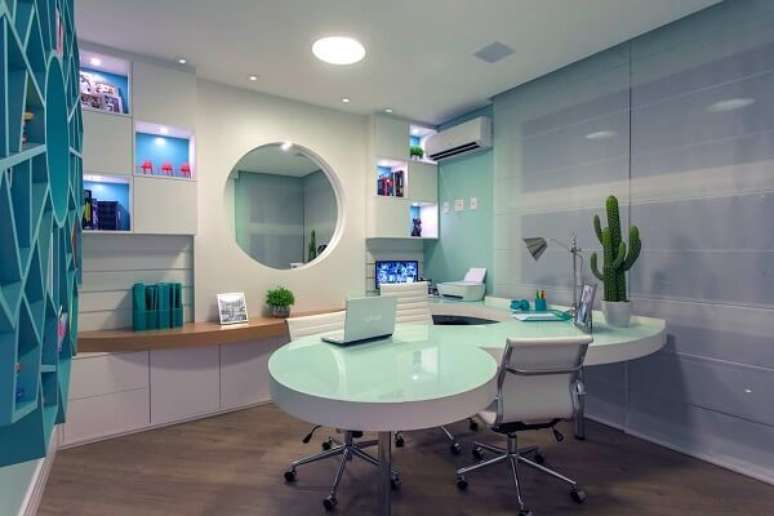 21. Consult&oacute;rio com nichos em marcenaria azul e mesa de vidro jateado. Fonte: Revista Viva Decora