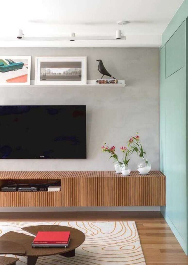 32. Sala de estar decorada com trilho de luz, parede de cimento queimado e rack de madeira moderno suspenso – Foto: Pinterest