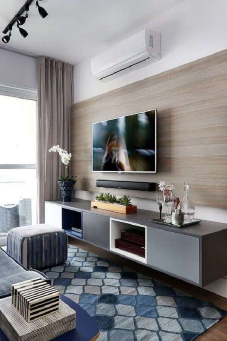 3. Sala pequena e moderna decorada com tapete azul e cinza e rack com painel de madeira – Foto: Pinterest