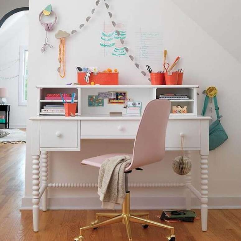 49. Escrivaninha branca decorada com cadeira giratória rosa claro com pé dourado – Foto: Crate and Kids