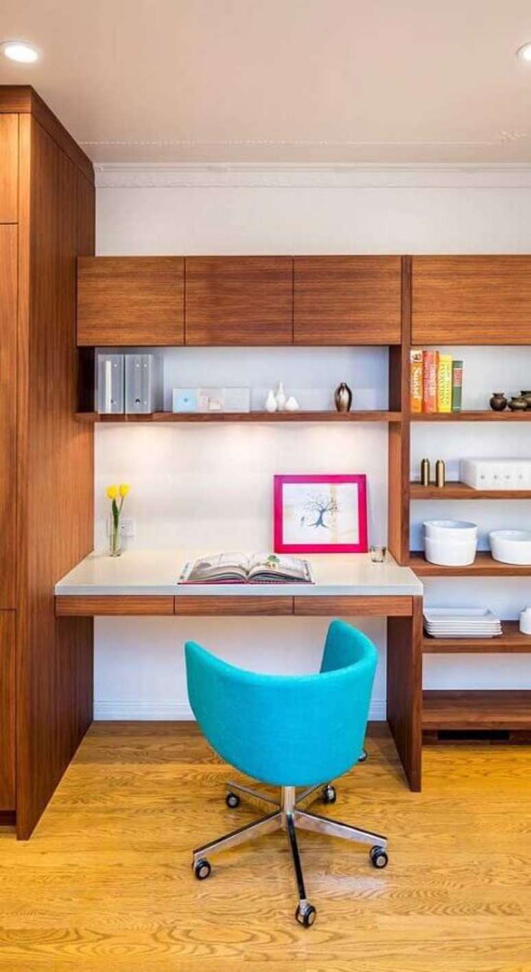 57. Home office todo decorado com armários de madeira e cadeira decorativa giratória azul – Foto: The Interior Collective