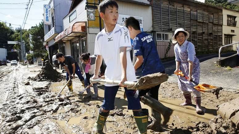 Estudantes e moradores removem lama depois de enchentes causadas por tufão Hagibis
