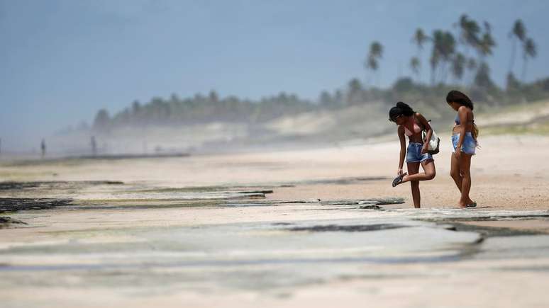 Banhistas em Conde, na Bahia; no Estado, órgão emitiu um alerta para que praias contaminadas com óleo sejam evitadas