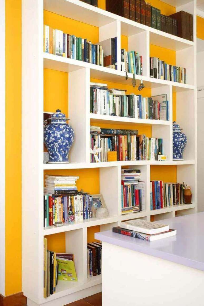 26. Esta parede de cor amarela combina muito com a estante branca. Projeto de Simone Collet