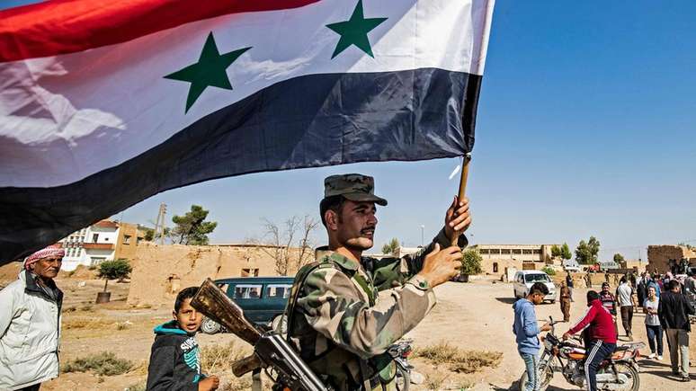 Um soldado do governo sírio agita a bandeira nacional