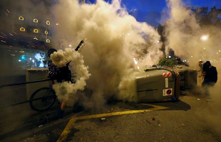 Manifestante joga bomba de gás lacrimogêneo de volta contra a polícia durante protestos em Barcelona
18/10/2019 REUTERS/Albert Gea
