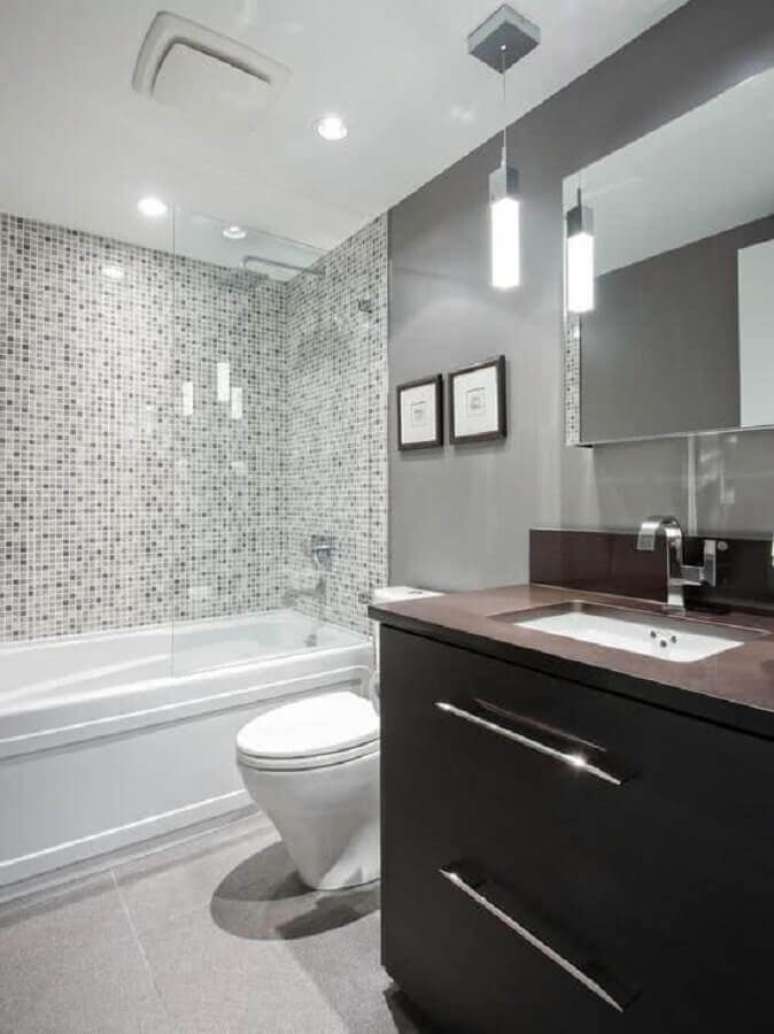 38. Banheiro cinza e branco decorado com gabinete de madeira escura – Foto: Decohoms
