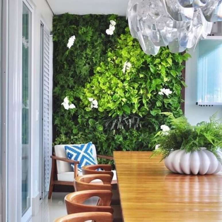 1. Sala de jantar com móveis de madeira e parede revestida com jardim vertical artificial. Fonte: Pinterest