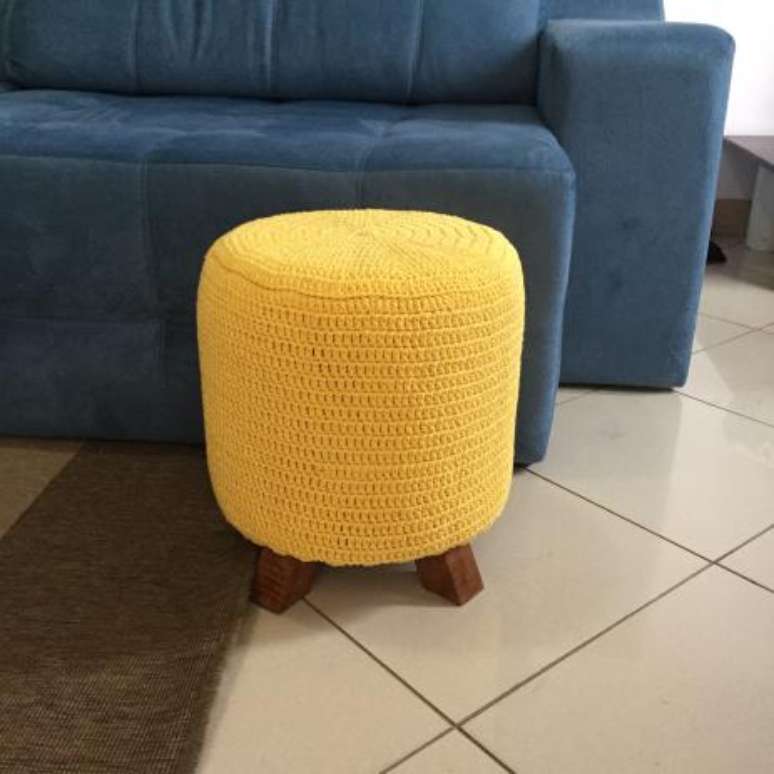 48. Puff de crochê amarelo combinando com o sofá azul marinho – Por: Magazine Luiza